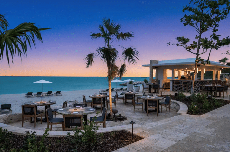 Elegant beachfront dining setup at a luxury resort during sunset, highlighting experiential travel and premium guest experiences central to luxury hotel marketing