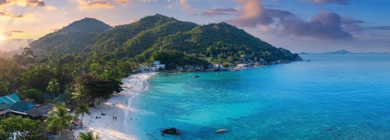 Panoramic view of a luxury resort set between mountains and the ocean at sunrise